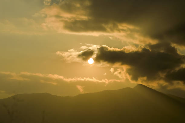 istock Dramatic dark heavily Red sunset clouds makes the sky romantic on one evening time of a day in Mid December. Sunlight reflection through clouds while clouds flying passing rolling or moving over the mountain range in a hill station of India. Silhouette 1171927322