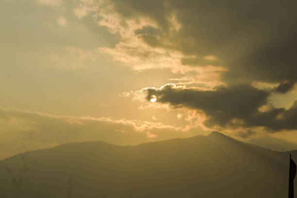 Dramatic dark heavily Red sunset clouds makes the sky romantic on one evening time of a day in Mid December. Sunlight reflection through clouds while clouds flying passing rolling or moving over the mountain range in a hill station of India. Silhouette