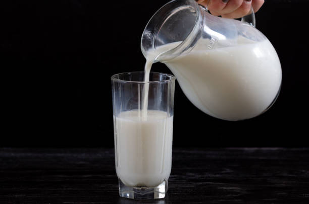 istock Milk in a glass jug is poured into a glass 1171929582