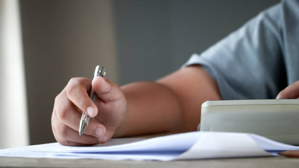 istock Education test exam in school concept : University student holding pen notes paper document sheet at lecture chair for taking exams in examination classroom. Assessment learning in class ideas 1171930805
