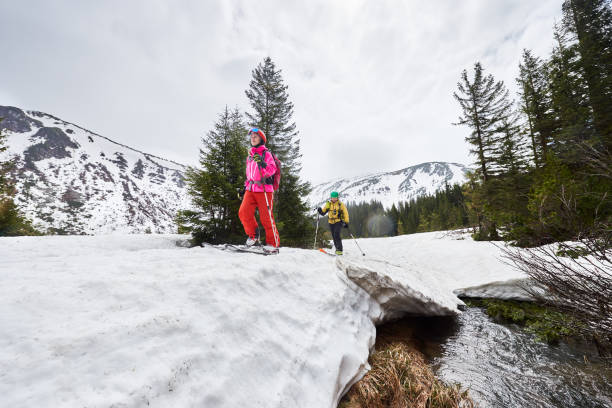 istock Small group of people sliding on ski on snow-covered bridge and flowing stream under picturesque snow-covered mountains 1171931002