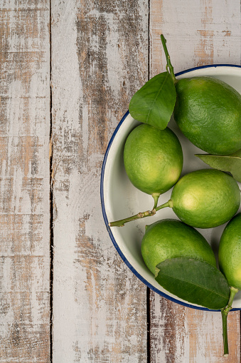 fresh green limes on a wooden table with copy space