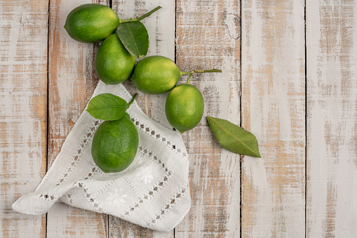 fresh green limes on a wooden table with copy space