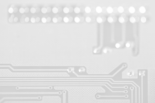 Close-up photo of an electronic circuit board in gray tones with copy space. Shallow depth of field, beautiful bokeh. Can be used as a background.
