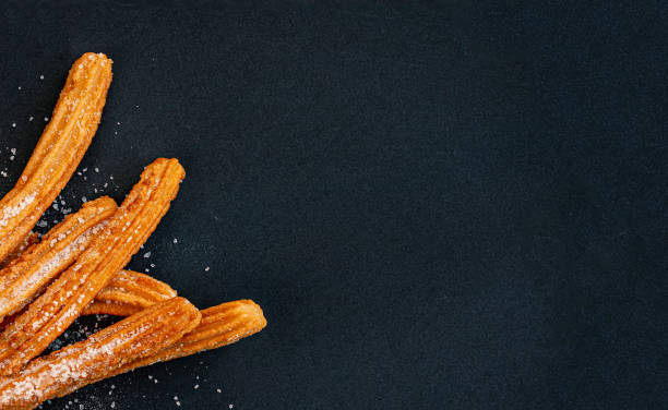 istock Churro on a black background. Traditional Spanish cusine. Churros in a paper bag with copy space. Top view 1171936313