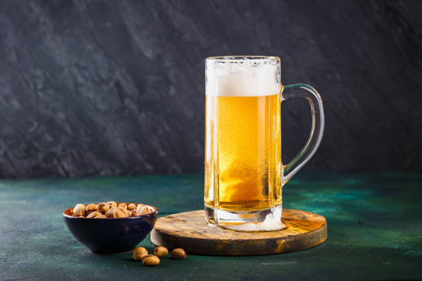 tazza di birra su sfondo scuro - beer nuts foto e immagini stock