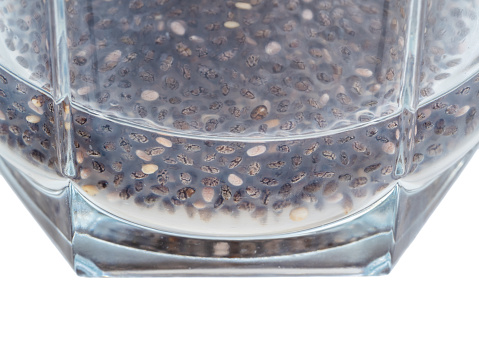 side view of chia seeds absorbed water and made gelatinous texture in glass close-up cutout on white background