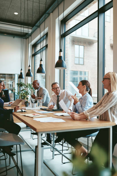 istock Laughing group of diverse businesspeople talking together around a table 1171946740