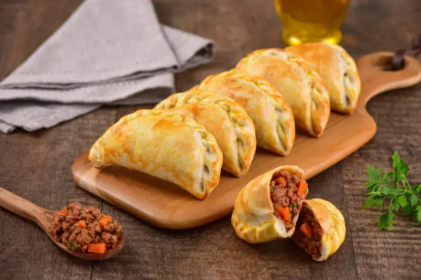 Meat roasted empanas on rustic board. Studio shoot on wooden background.