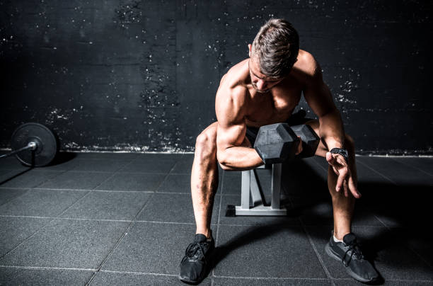 istock Young strong sweaty man biceps workout training with heavy dumbbell in the gym dark image with shadows real people 1171948028