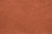 Full frame image of textured stucco in bright terracotta color