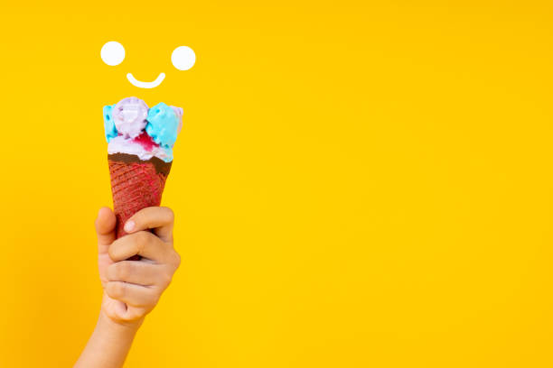 istock Close up hand holding colorful ice cream cone on yellow background with copy space 1171950580