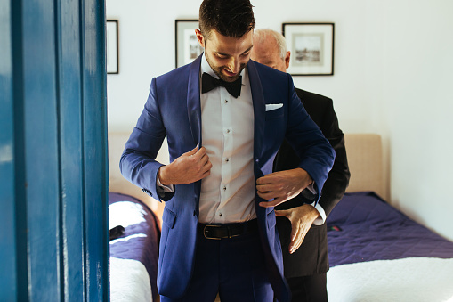 Father helping groom son with his suit