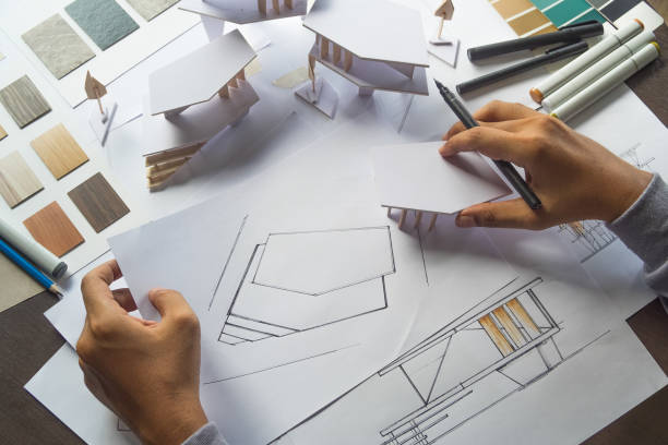 istock architect design working drawing sketch plans blueprints and making architectural construction model in architect studio 1171952540