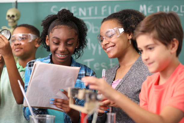 Junior high age school students conduct science experiments in classroom. Junior high, high school age students work on science experiments in school classroom setting.  STEM topics.  Laboratory glassware, microscope. high school high school student science multi ethnic group stock pictures, royalty-free photos & images