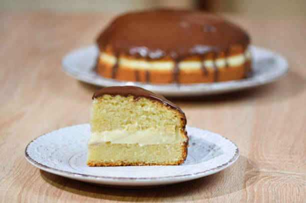 pezzo di torta alla crema di boston di fronte con l'intera torta sullo sfondo. - torta alla crema foto e immagini stock