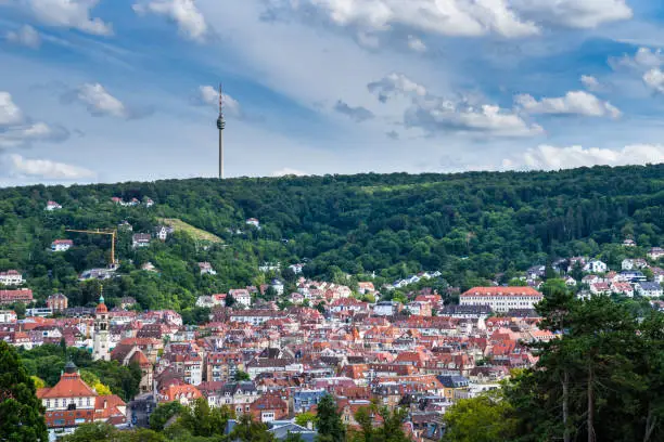 Germany, Cityscape stuttgart of red roofs of houses in basin surrounded by green forest and decorated with television tower on a hill