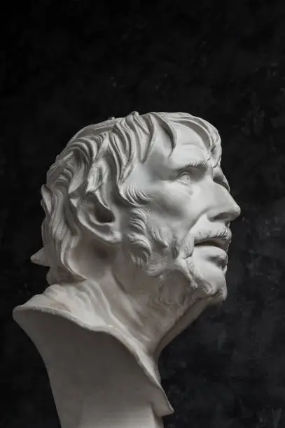 White gypsum copy of ancient statue of Lucius Seneca head for artists on a dark textured background. Seneca 4 BC-65 AD Roman stoic philosopher, statesman and tutor to the future Emperor Nero.