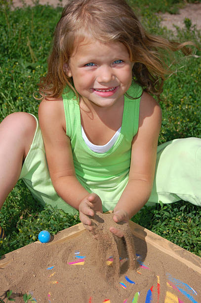 Young pretty girl playing with sand stock photo