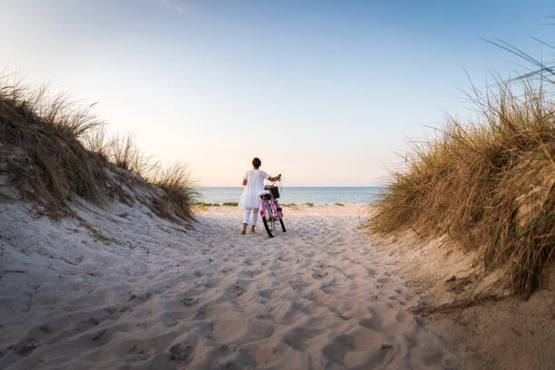 Woman with bike on beach at sunset Woman with bike on beach at sunset baltic sea stock pictures, royalty-free photos & images