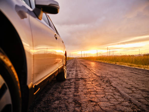 A car on an open rural road at sunset.
