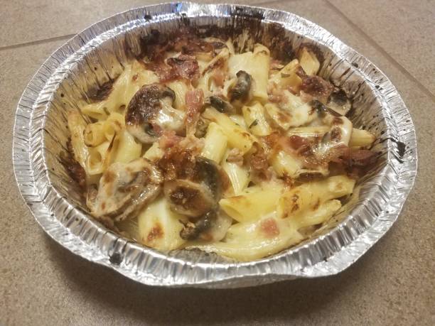 istock penne pasta with bacon and mushrooms in foil plate on tile floor 1171982936
