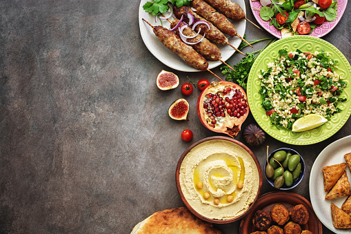 Arabic and Middle Eastern dinner table. Hummus, tabbouleh salad, Fattoush salad, pita, meat kebab, falafel, baklava, pomegranate. Set of Arabian dishes.Top view, copy space.