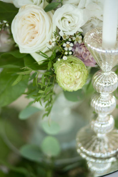 istock Wedding table setting is decorated with fresh flowers and white candles. Wedding floristry. Bouquet with roses, hydrangea and eustoma. Table numbering 1171984449