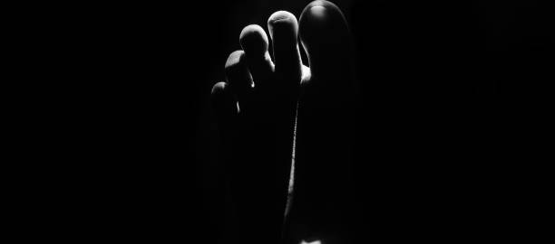 istock Fingers of a human legs with black background 1171985245