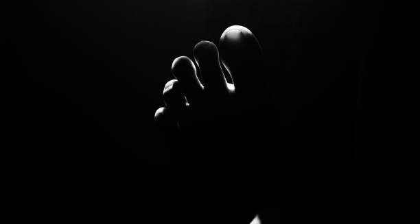 istock Fingers of a human legs with black background 1171985246