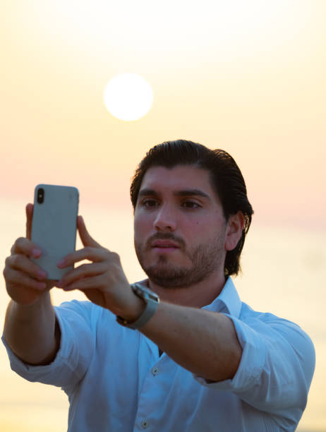 istock Man enjoying colorful sunset or sunrise, taking selfie 1171987337