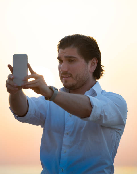 istock Man enjoying colorful sunset or sunrise, taking selfie 1171987354