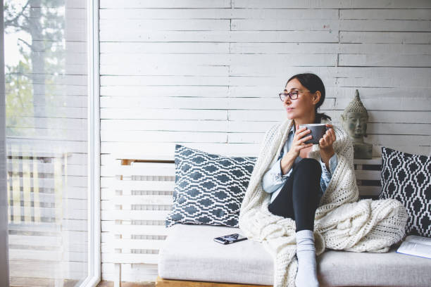 istock Woman sitting comfortable drinking tea and looking through window 1171989688
