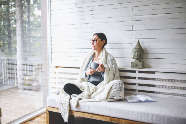 istock Woman sitting comfortable drinking tea and looking through window 1171989728