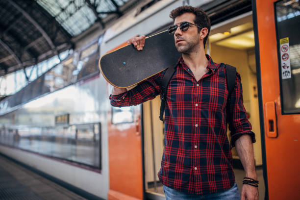istock Man with skateboard on a train station 1171989917