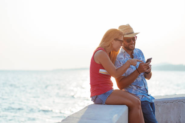 istock Young happy couple using smartphone by the sea 1171990026