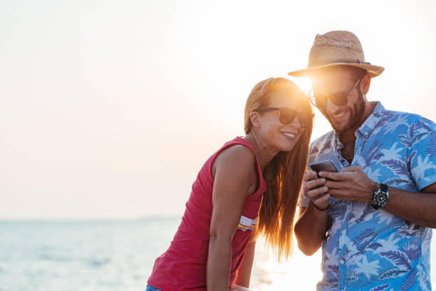 istock Young happy couple using smartphone by the sea 1171990030
