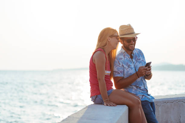 istock Young happy couple using smartphone by the sea 1171990034