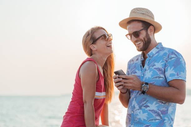 istock Young happy couple using smartphone by the sea 1171990037