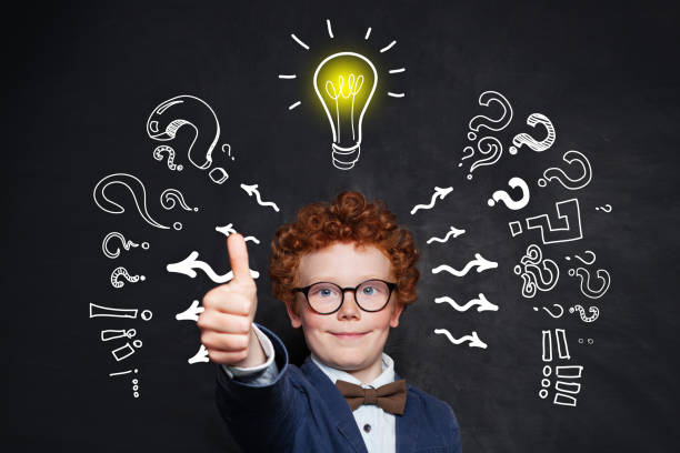 istock Cute kid holding thumb up with lightbulb on blackboard background 1171991797