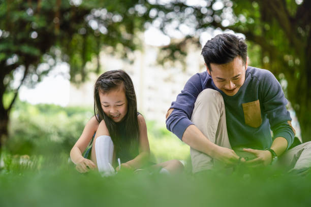istock Man with girl tying shoelace while sitting at park 1171993566