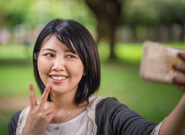 istock Smiling woman taking selfie with phone at park 1171993899