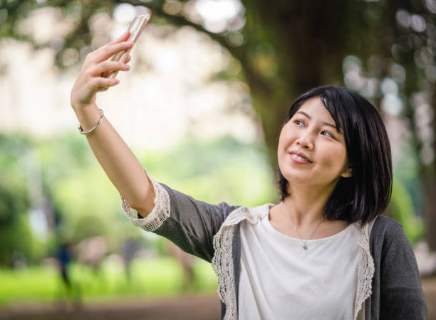 istock Smiling woman taking selfie with phone at park 1171994436