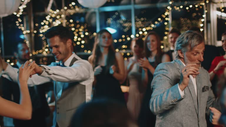 Newlyweds dancing with guests at wedding party