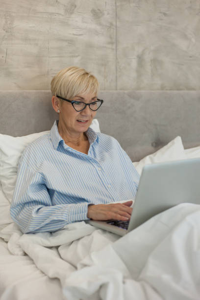 istock Senior woman lying in bed and using laptop 1172004562