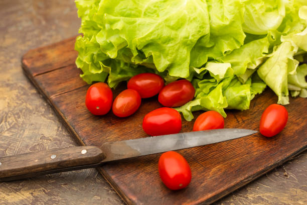 Cutting vegetables. Green lettuce and cherry tomatoes on an old cutting board. Diet food