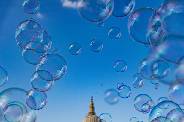 Large multicolored soap bubbles flying in the cloudy sky. Big bubble outdoors in the spring or summer street. Frankfurt, Alte Oper on background. Simple creative concept. Close-up. Copy space