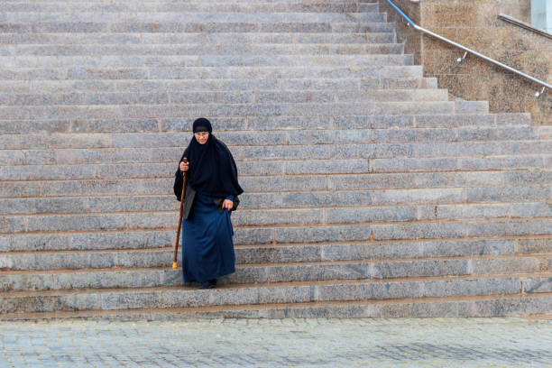 elderly orthodox nun walking down stairs from the cathedral - confessional nun imagens e fotografias de stock