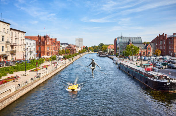 Bydgoszcz, Poland - August 25, 2019: Bydgoszcz cityscape seen from a bridge with tightrope walker sculpture over Brda River.