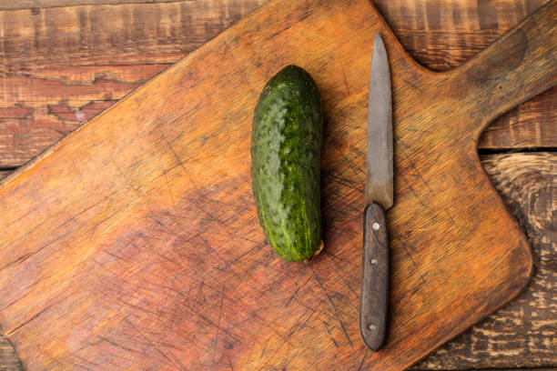 Fresh cucumber and knife on a wooden cutting board. View top. Copy space